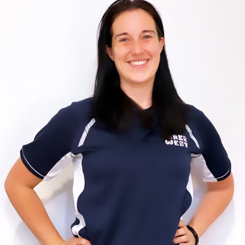 Personal trainer Sarah standing with hand on hips smiling wearing a navy blue shirt branded with Inner West Aquatics logo